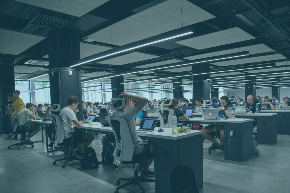 Großraumbüro mit vielen Arbeitsplätzen, an denen Teams an Laptops arbeiten